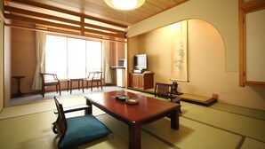 A traditional Japanese room with tatami flooring, a low wooden table, and a television. - Hotel Tappi (Sotogahama)