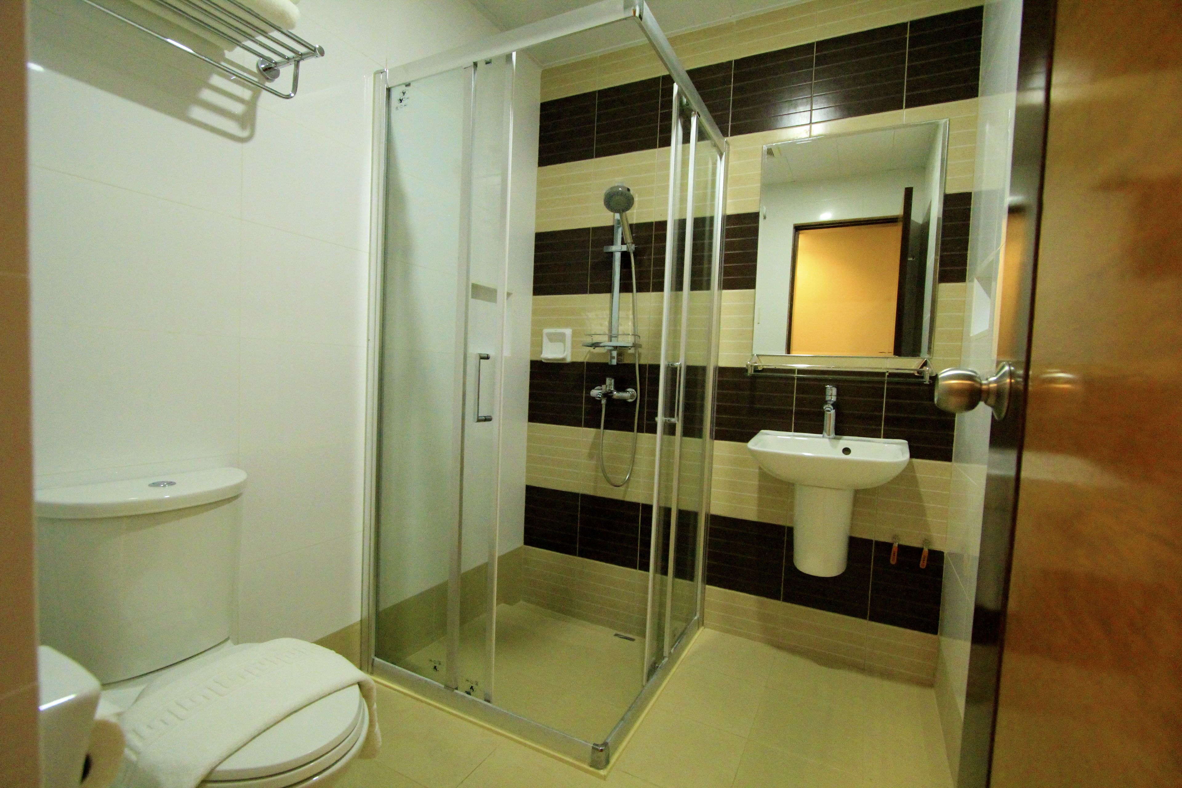 Un baño con ducha de vidrio, lavamanos blanco y retrete.