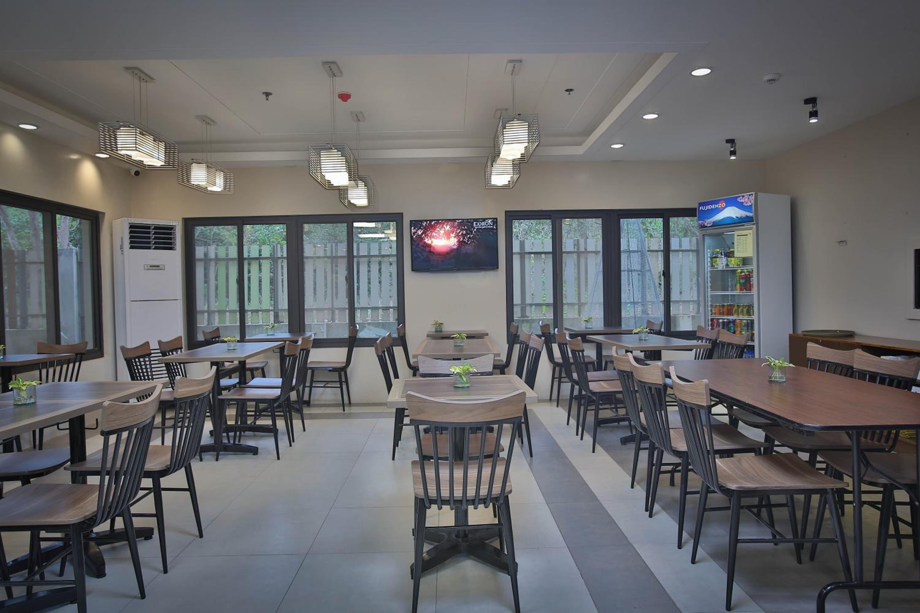 A spacious dining area with multiple tables and chairs, large windows, and a vending machine.
