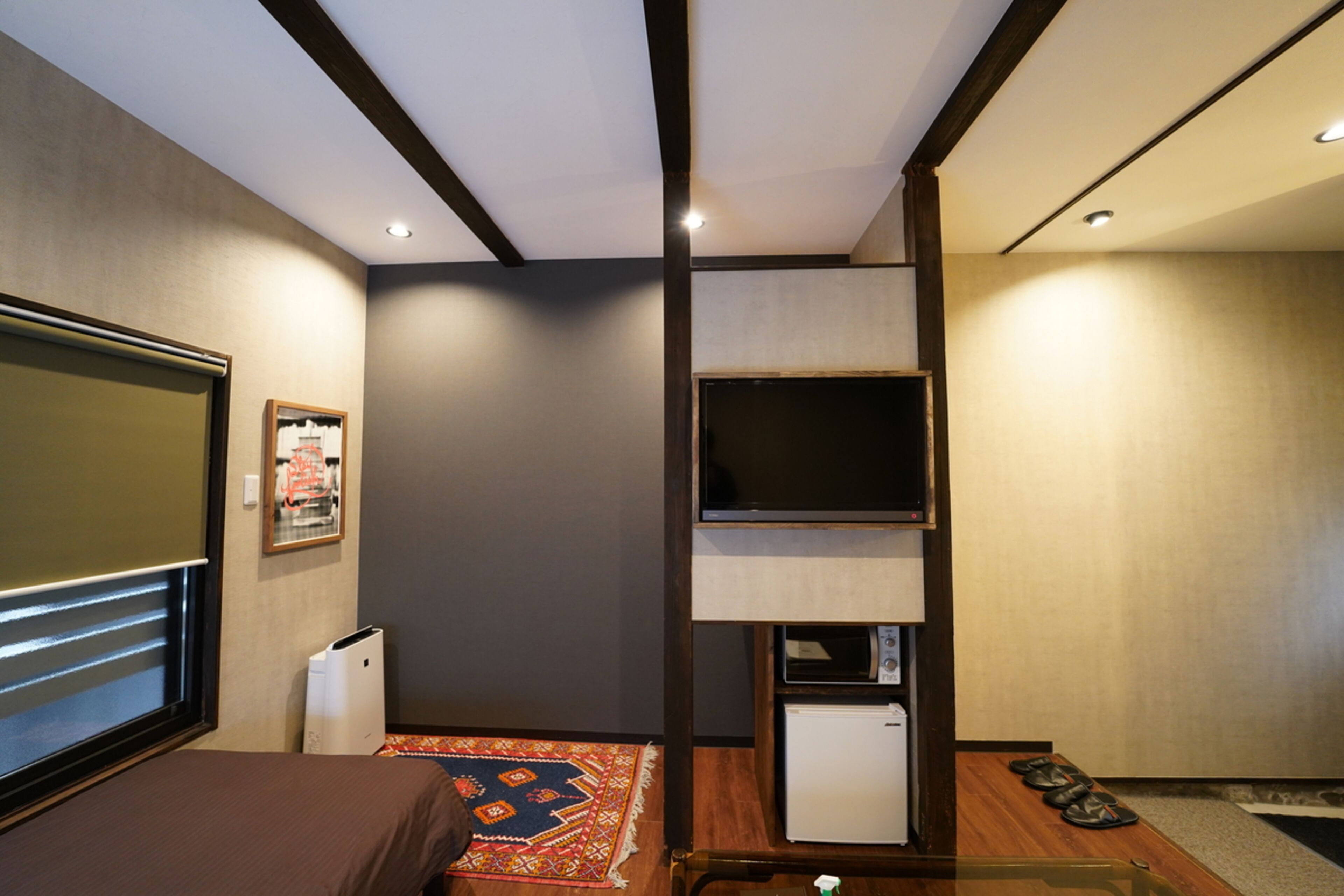 A hotel room with a bed, a television, a small refrigerator, and a microwave.