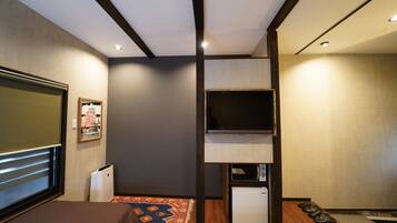 A hotel room with a bed, a television, a small refrigerator, and a microwave.