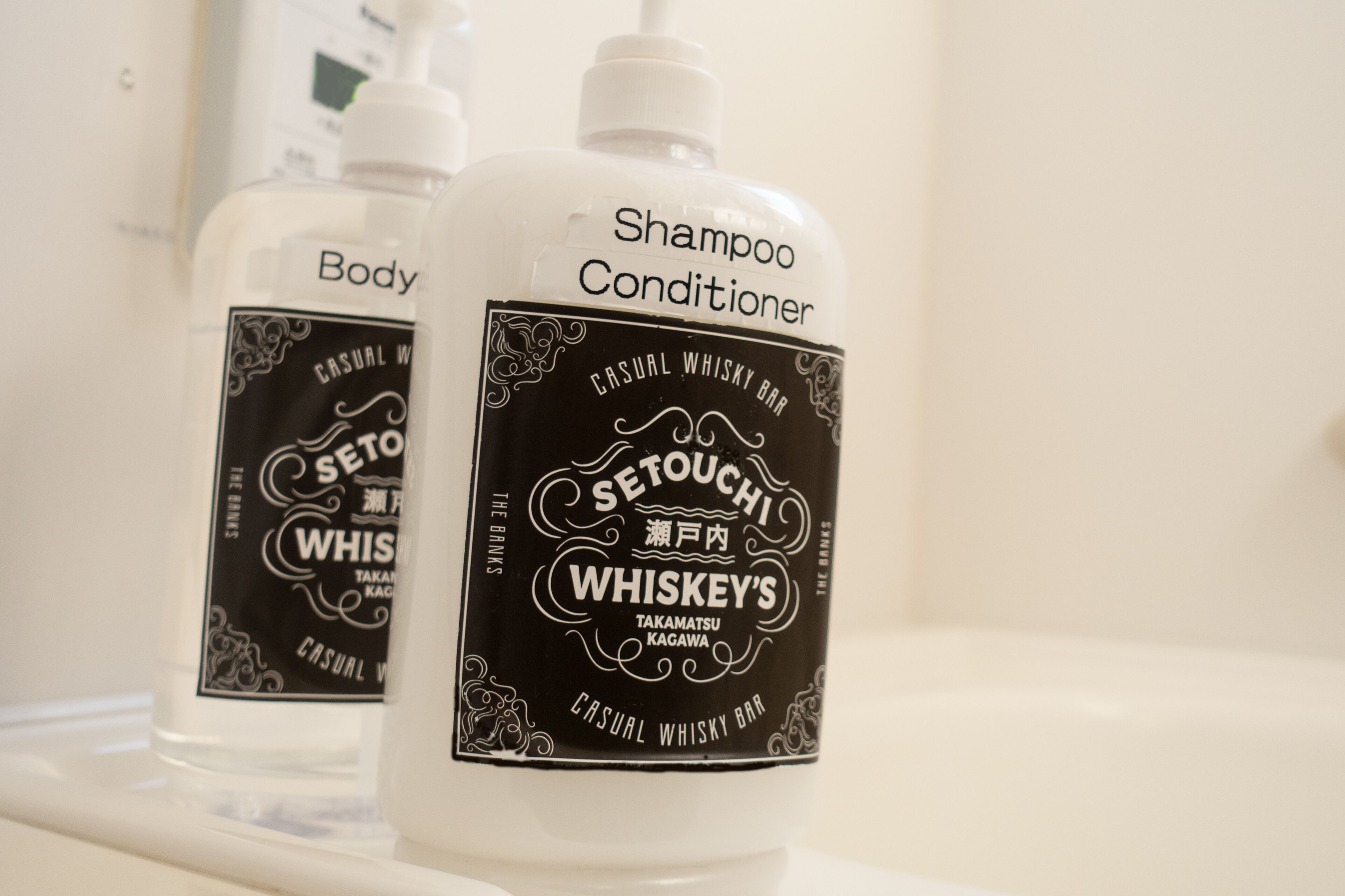 Dos botellas de acondicionador y champú Casual Whisky Bar de Setouchi Whiskey sobre una encimera de baño.