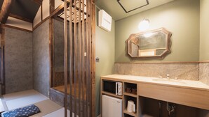 Una habitación tradicional japonesa con suelo de tatami, puertas correderas de madera, un lavamanos empotrado y un espejo con marco decorativo.