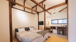 Un dormitorio con dos camas, un escritorio, una silla, un televisor y una ventana.