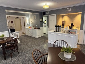 A modern kitchen with white cabinetry, a dining area with wooden chairs, and a small island with kitchen appliances and utensils.