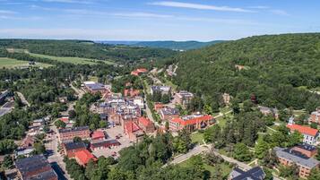 An aerial view of a campus with multiple buildings, green spaces, and a hilly landscape in the background.