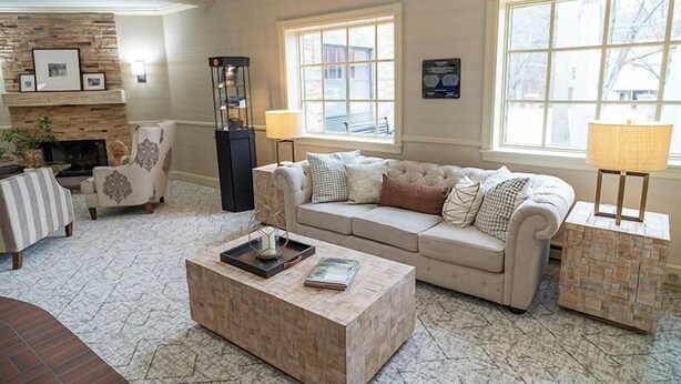 A spacious living room with a fireplace, a large window, and a comfortable seating area. - Saxon Inn (Alfred)
