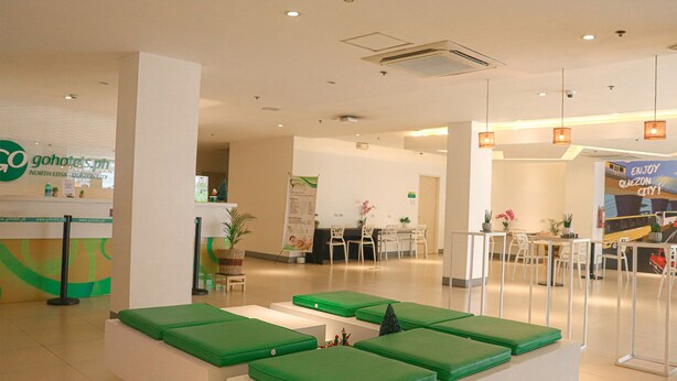A hotel reception area with a green seating area, a reception desk, and a sign for 'gohotel's.ph'. - Go Hotels North Edsa (Quezon City)