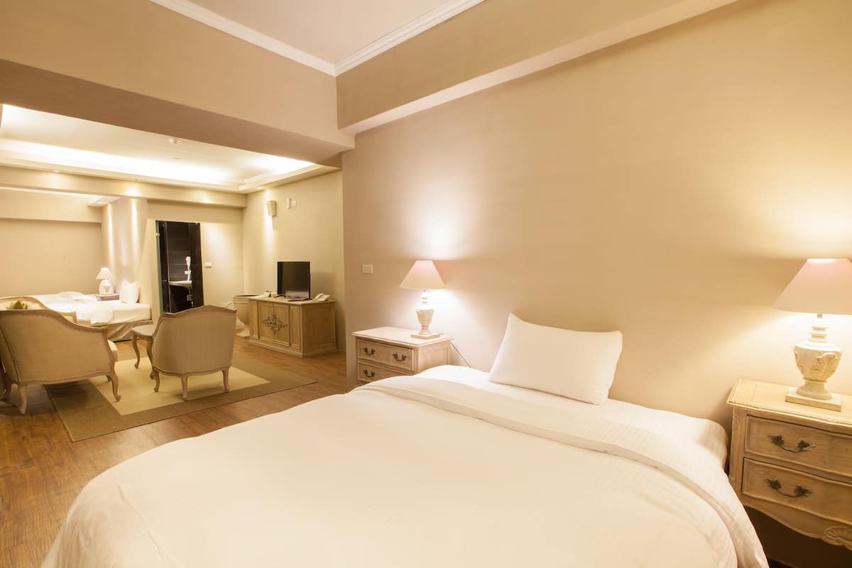 Habitación de hotel con una cama grande, mesitas de noche con lámparas, un escritorio con silla y un televisor.