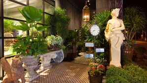 A well-lit outdoor area with potted plants, a statue, a clock, and a sign indicating the entrance to a hotel. - Hotel Royal Kingdom (Beinan)