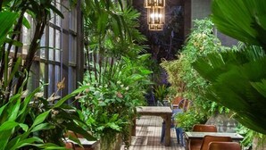 An indoor garden with tables and chairs, surrounded by lush green plants and decorative hanging lights. - Hotel Royal Kingdom (Beinan)