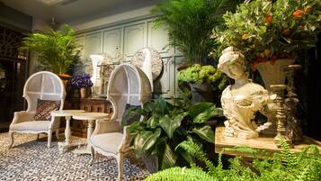 Una habitación con muebles antiguos, una estatua y abundante vegetación.