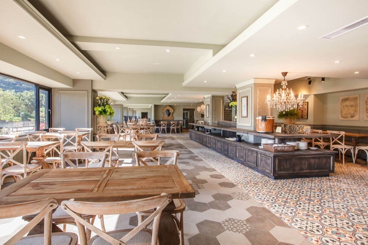 A spacious dining area with wooden tables and chairs, a patterned floor, and a central island with seating.
