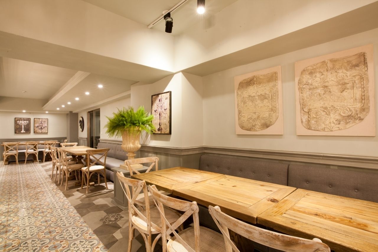 Un comedor amplio con una larga mesa de madera, asientos acolchados y un tapete estampado.
