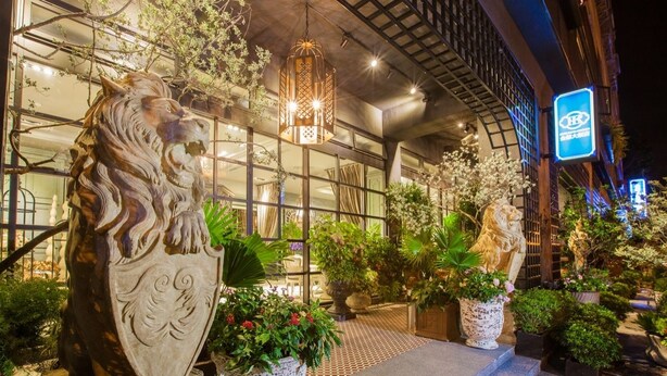 A building with large lion statues, a modern glass facade, and a well-lit entrance area with potted plants. - Hotel Royal Kingdom (Beinan)