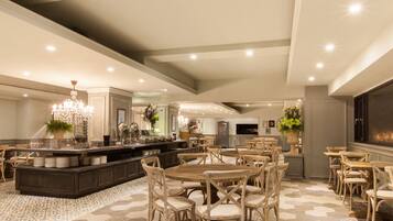 A spacious, elegantly decorated hotel lobby with a central island, multiple seating areas, and a large chandelier.