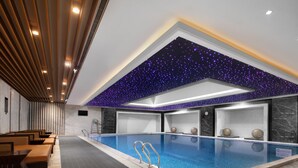 Ein moderner, überdachter Poolraum mit Sternenhimmel, einer Lounge mit Sitzgelegenheiten und ungehinderter Pool-Sicht.