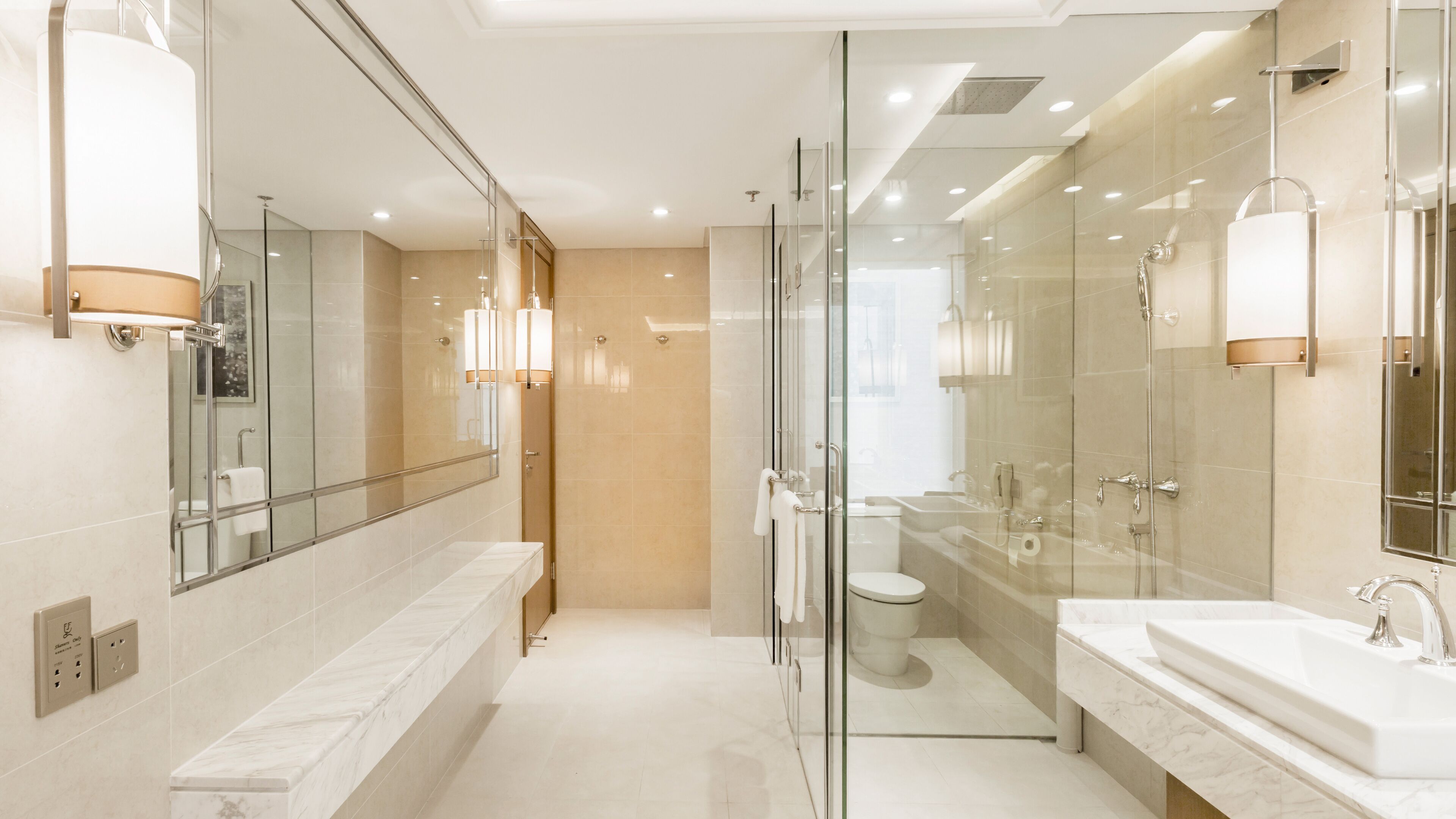 A modern bathroom with a glass shower enclosure, a separate toilet, and a vanity with a sink.