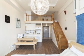 A modern apartment with a loft bedroom, a kitchen with a washing machine, and a dining area.