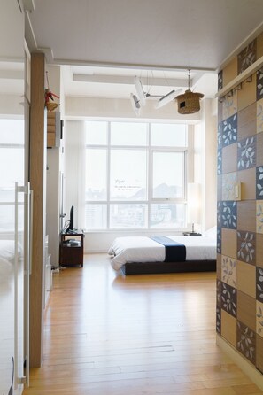 A bedroom with a large window, a bed, a desk with a computer, and a hanging basket. - 202 House Seoul Station (Seoul)