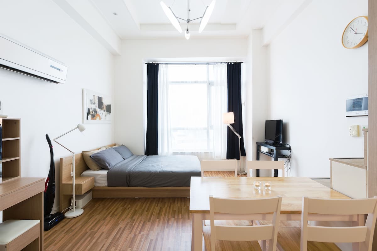 Una habitación moderna y luminosa con una cama, un escritorio y una mesa de comedor.