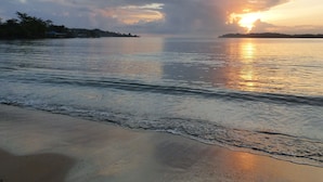 A beach with calm waters reflecting the sunset. - Sand Dollar Beach Bed & Breakfast (Bocas del Toro)