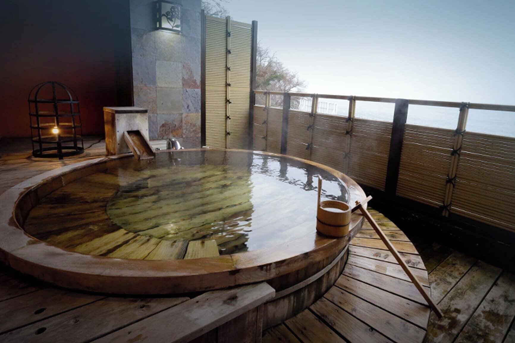 A hot tub on a wooden deck with a view of the sea.