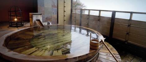 A hot tub on a wooden deck with a view of the sea.