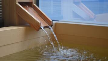 A wooden water feature with water flowing into a basin.