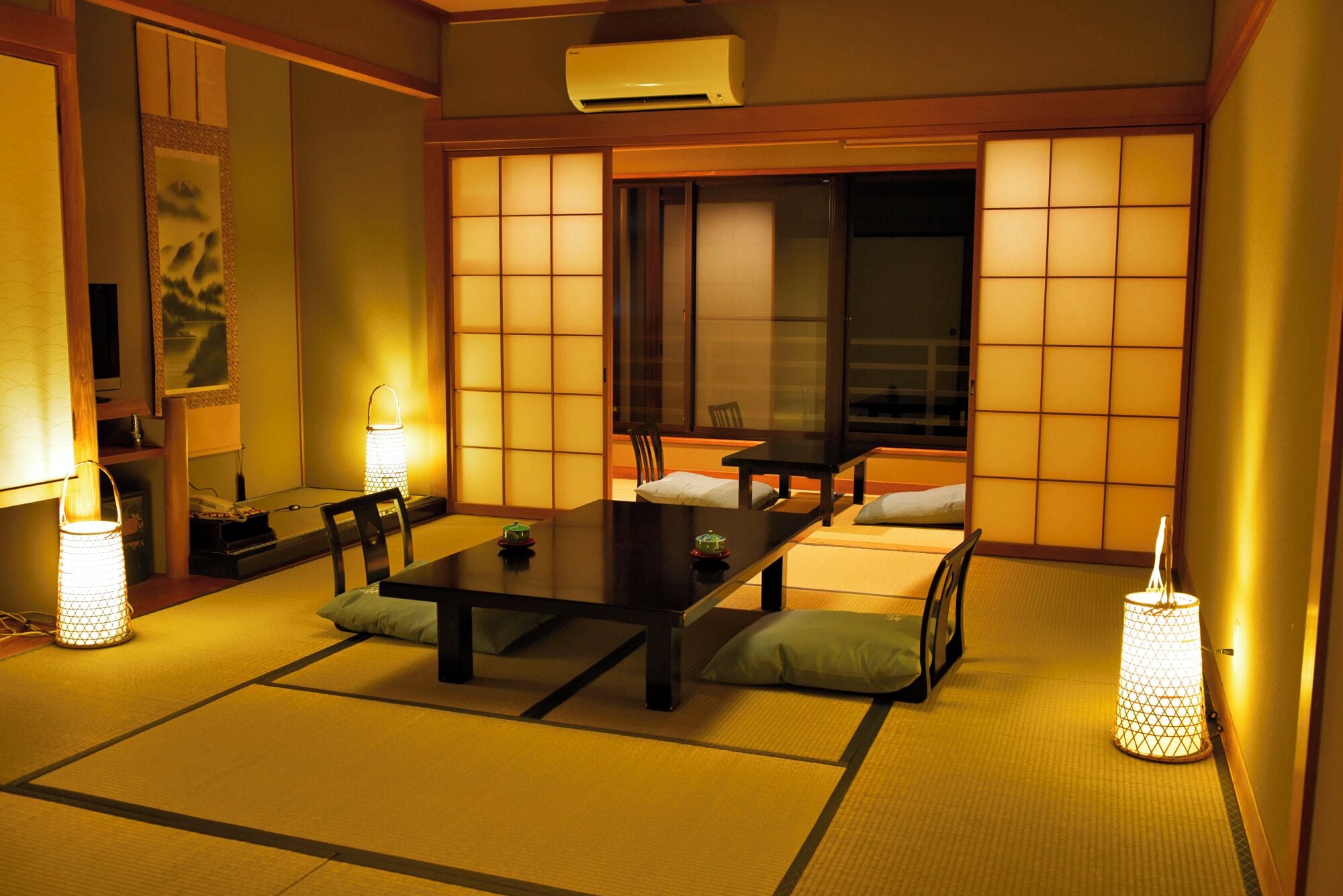 A traditional Japanese room with tatami flooring, a low table, cushions, and shoji screens.