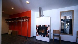 A modern living room with a fireplace, a red accent wall, and a wooden chair. - Äijälän Rusti Paratiisisaari (Naantali)