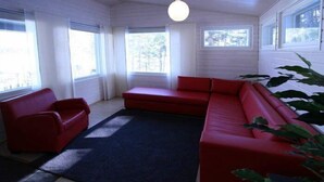 A room with a red sofa, a red armchair, and a large window. - Äijälän Rusti Paratiisisaari (Naantali)