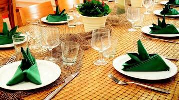 Una mesa de comedor dispuesta con servilletas verdes, vasos transparentes y platos blancos.