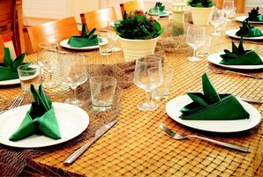 Una mesa de comedor dispuesta con servilletas verdes, vasos transparentes y platos blancos.
