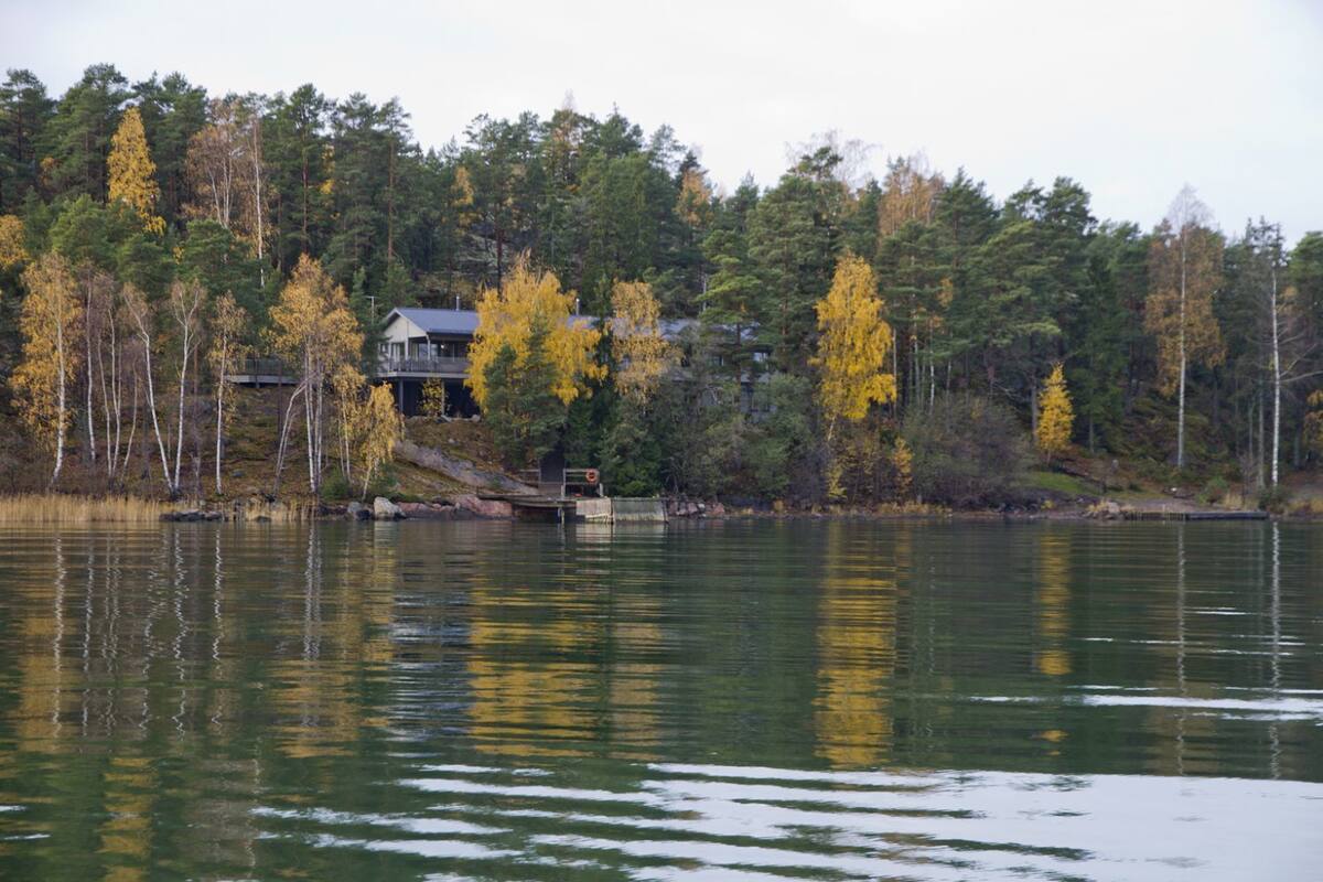 A lakeside cabin with a dock, surrounded by autumn-colored trees.