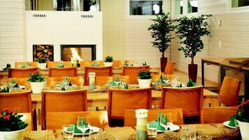 A dining area with multiple tables set for guests, featuring wooden chairs and tables with woven placemats.
