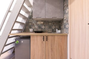 Compact kitchen with modern design, featuring a stainless steel sink, grey cabinet, and patterned tile backsplash.