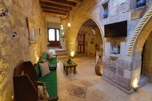Un interior acogedor con chimenea de piedra, muebles de madera y un televisor montado en la pared.