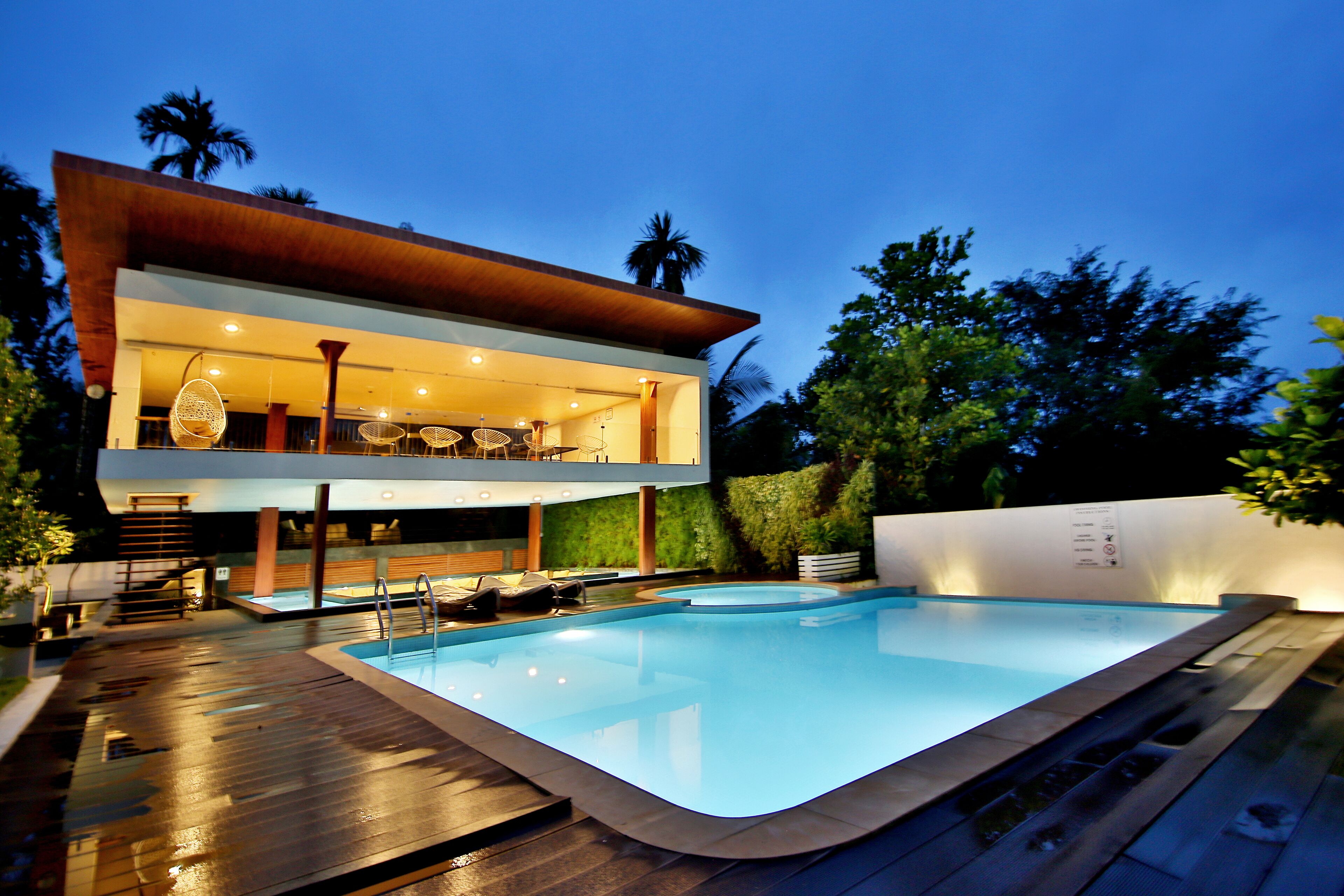 Una moderna casa a due piani con piscina, area salotto esterna e patio ben illuminato.
