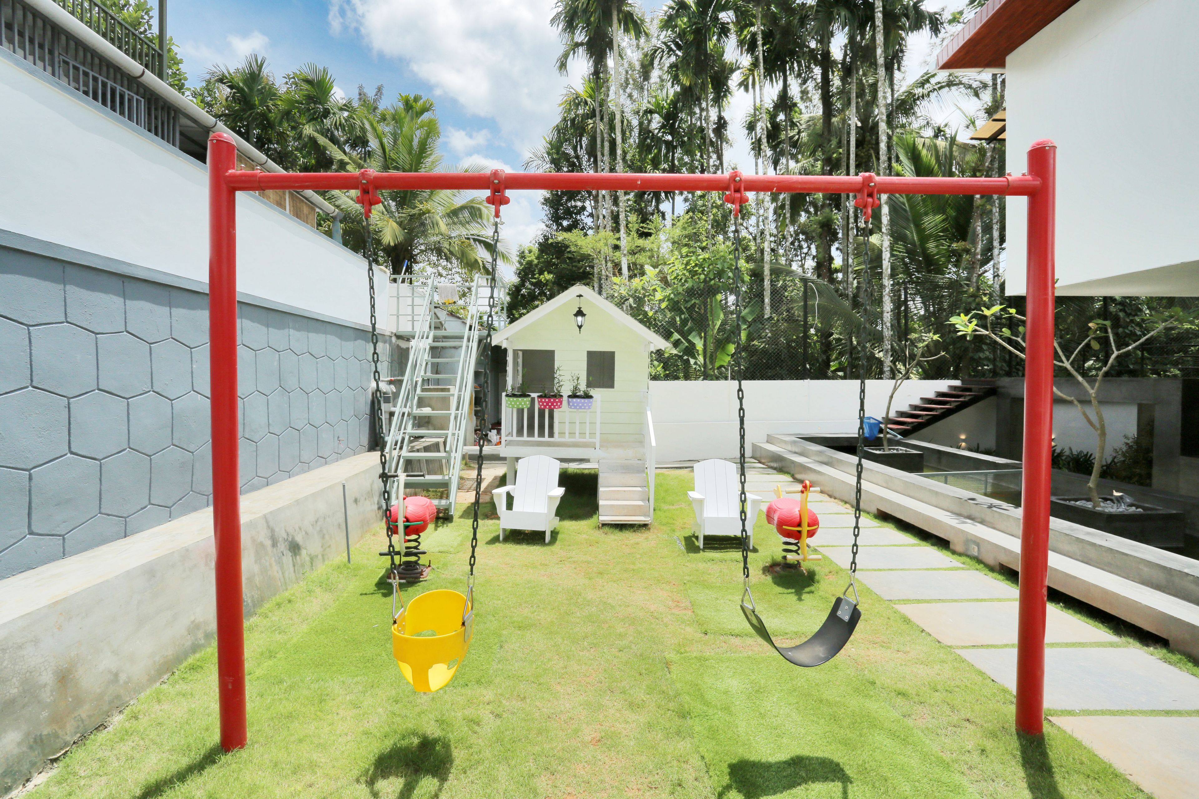 Ein Garten mit Schaukel, einem kleinen Haus und einer Treppe zu einer Terrasse.