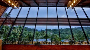 A room with large windows, a brick wall, and a view of a lush landscape.