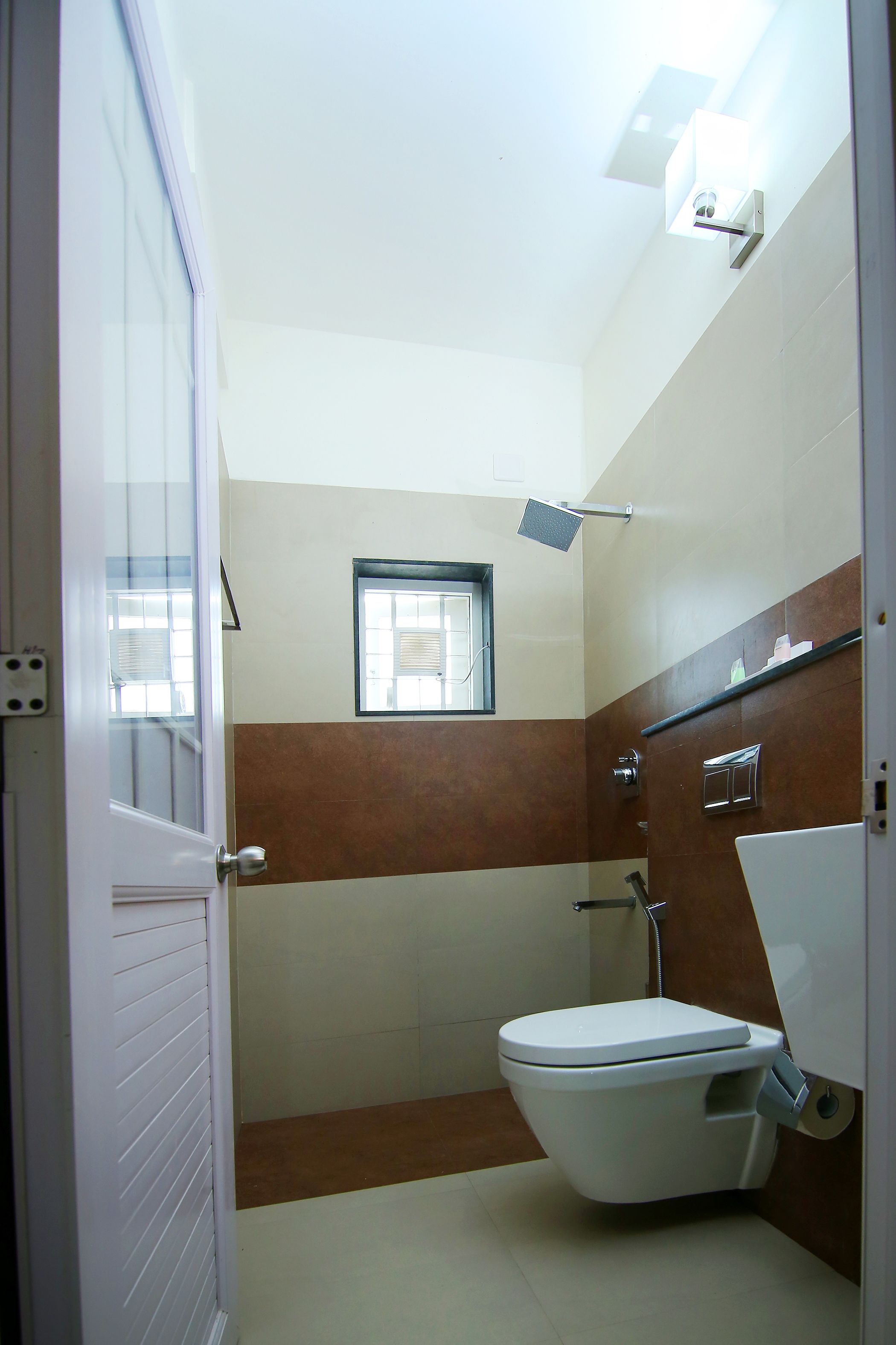 A small bathroom with a toilet, a shower, and a window.