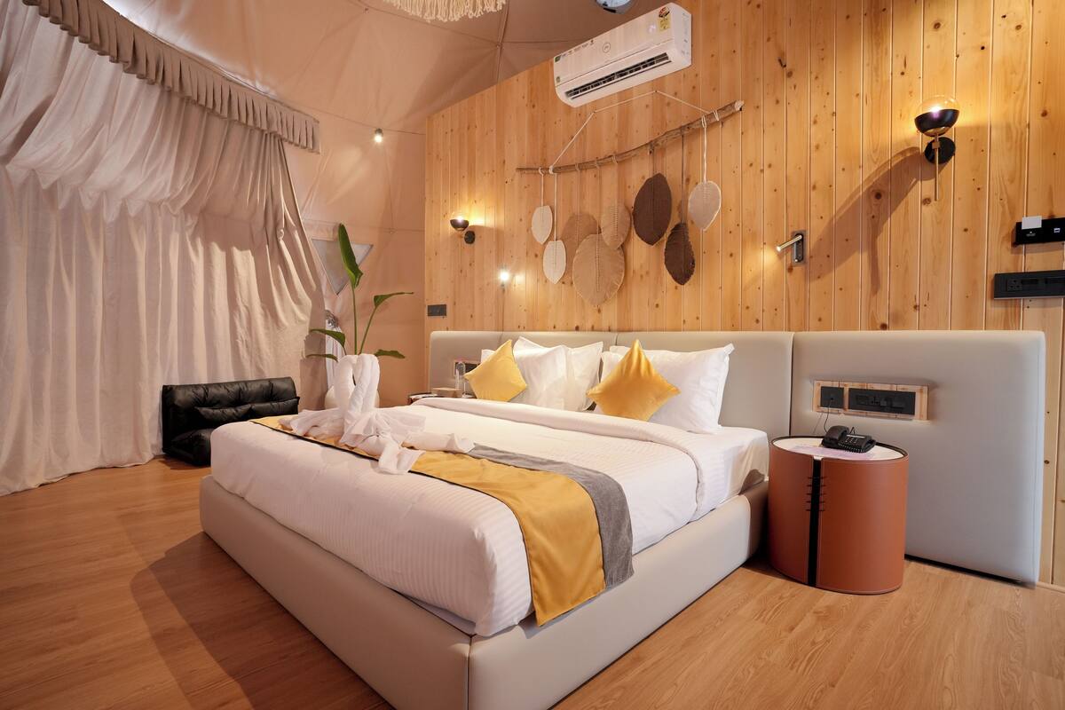 Ein modernes Hotelzimmer mit einem großen Bett, Holzwandverkleidung und einem kleinen Nachttisch.