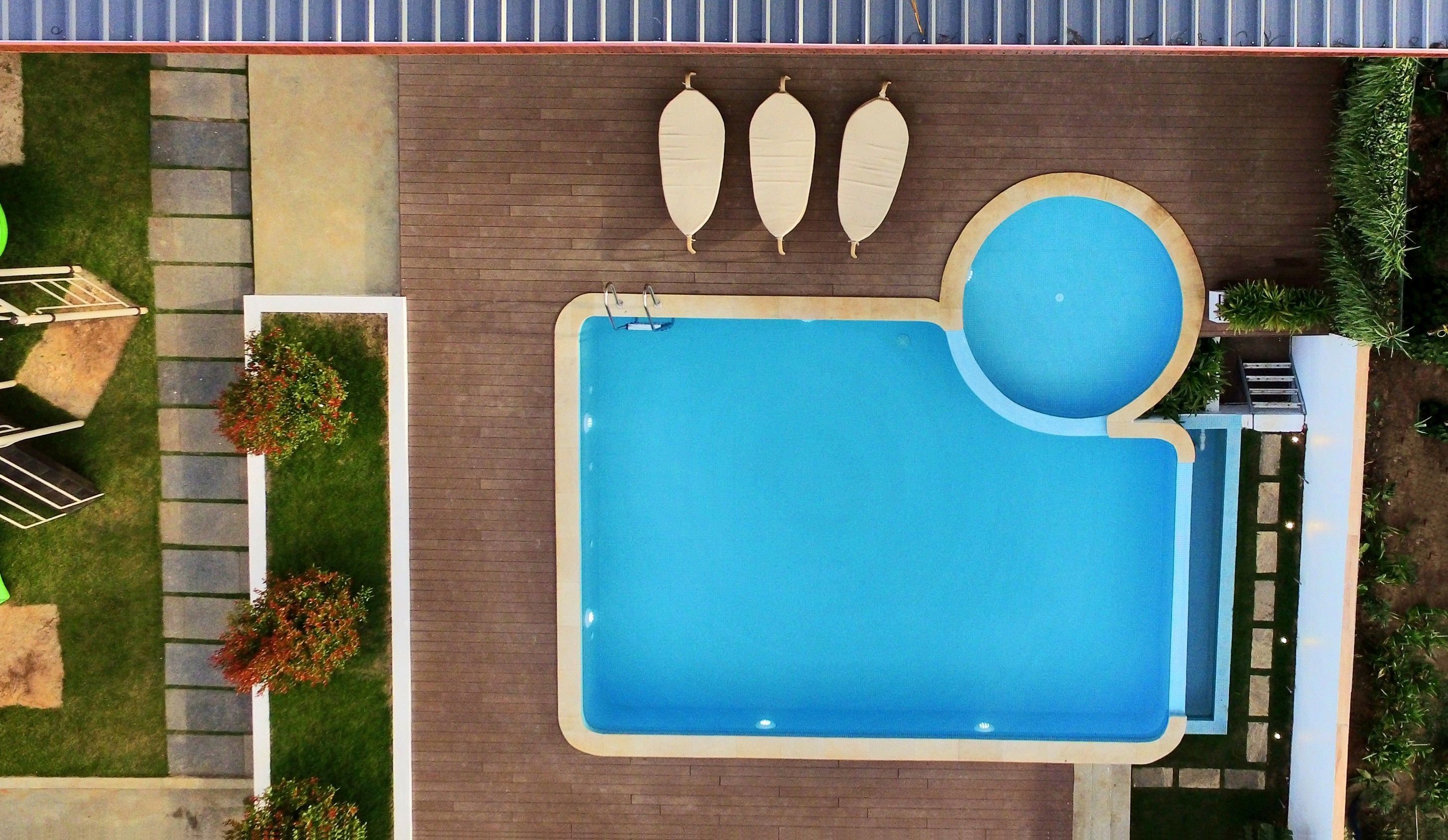 Una piscina rectangular con un jacuzzi circular, rodeada por una terraza de ladrillo.