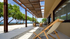 A covered outdoor seating area with a view of the beach and ocean. - Kouvohori Villas Crete (Hersonissos)