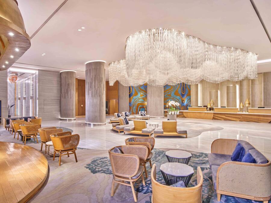 A spacious lobby with a large chandelier, seating areas, and a reception desk.