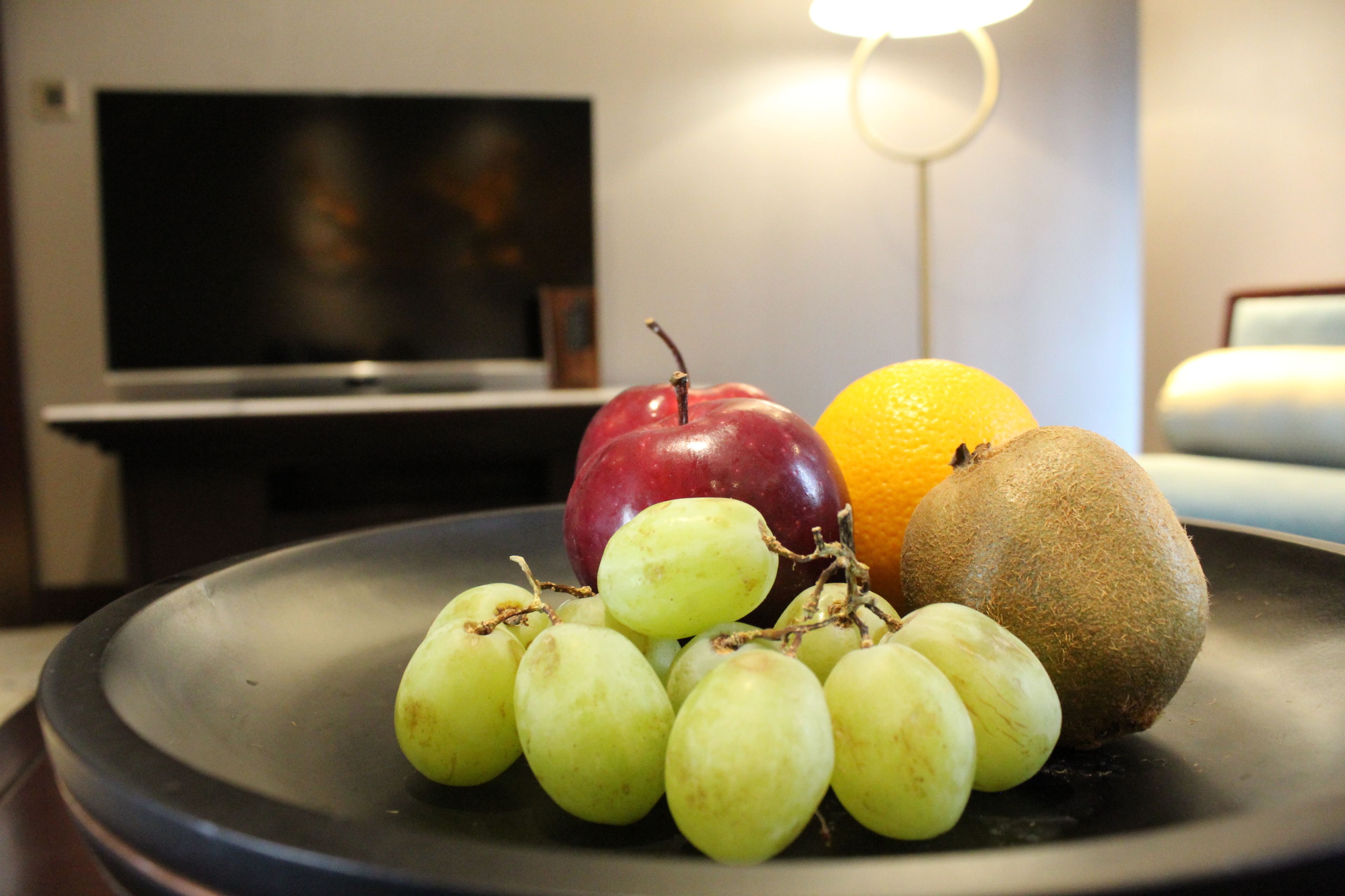 A fruit platter on a table with a television in the background.