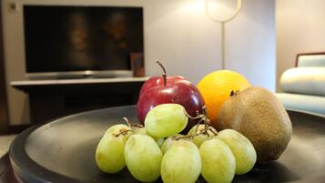 A fruit platter on a table with a television in the background.