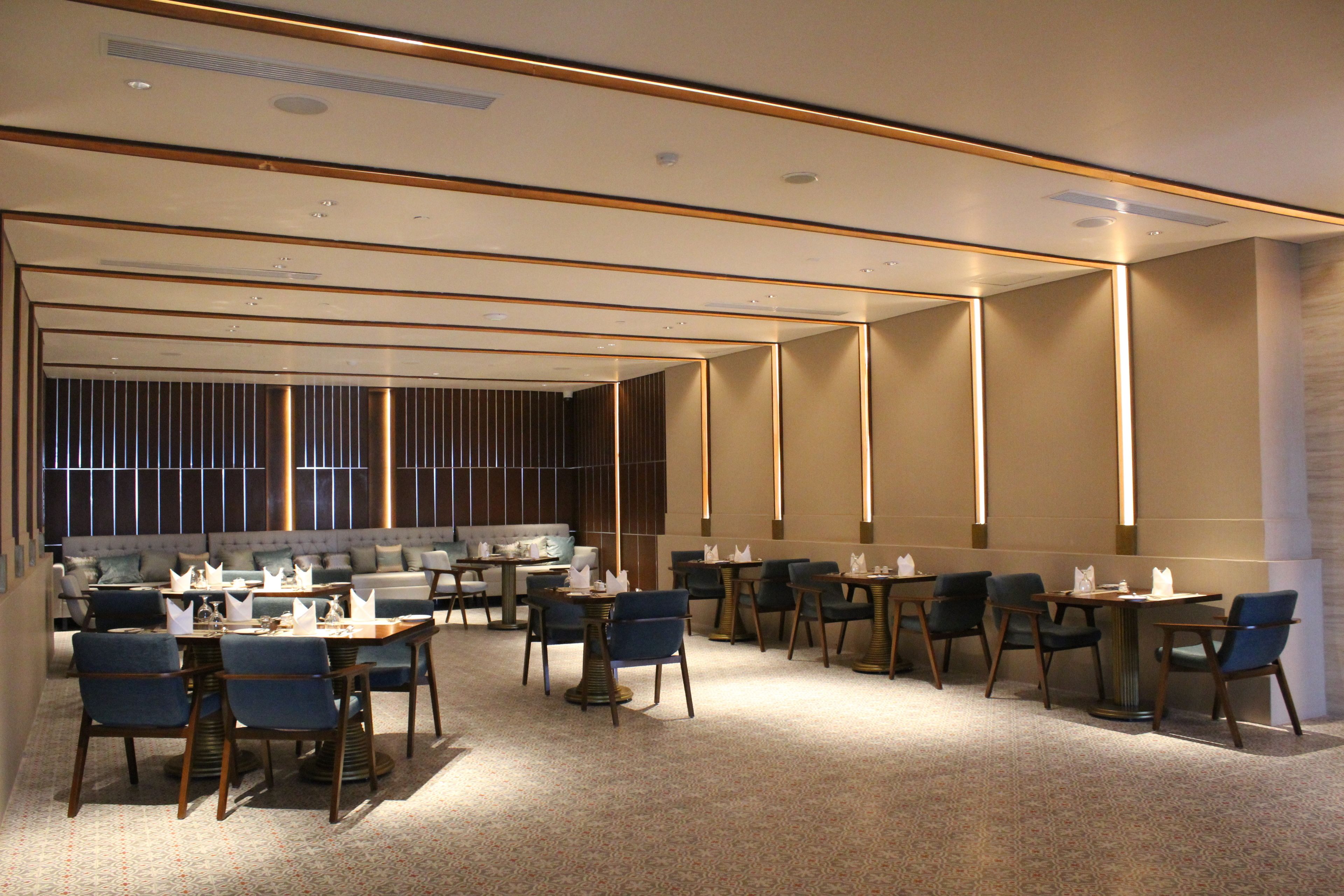 A modern hotel lobby with a seating area, tables, and a bar.