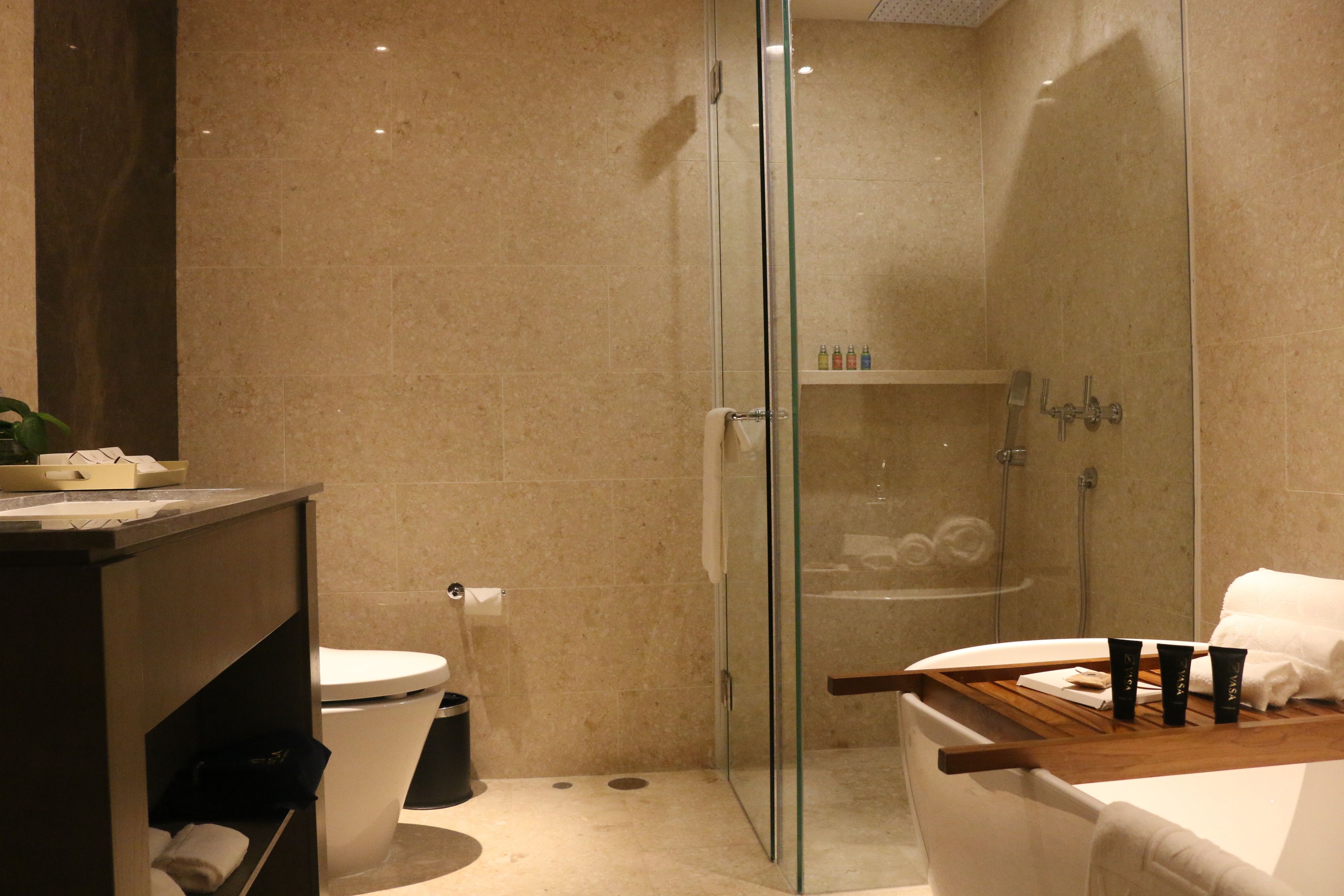 A modern bathroom with a glass-enclosed shower, a white toilet, and a vanity with a mirror.